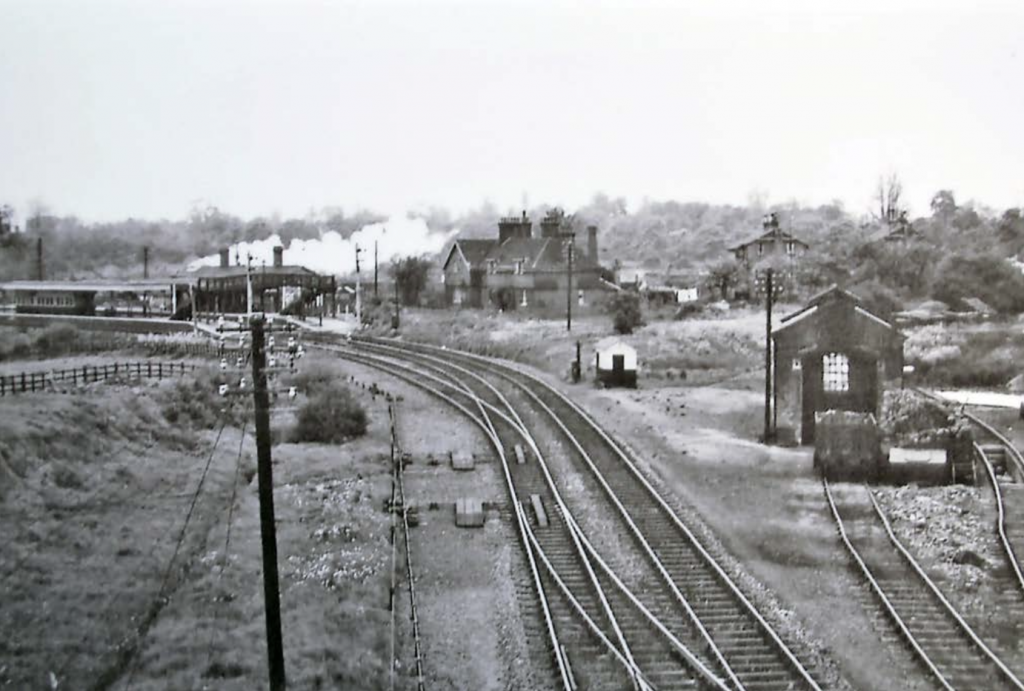 black and white historic photograph showing the station and train track